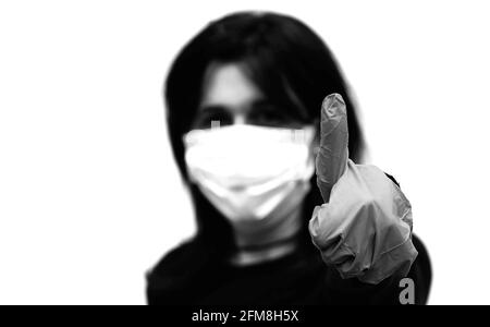 Black and White portrait of young woman with thumb up and surgical mask to protect herself from Corona Virus Stock Photo
