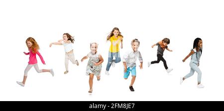 Group of elementary school kids or pupils running in colorful casual clothes on white studio background. Creative collage. Stock Photo