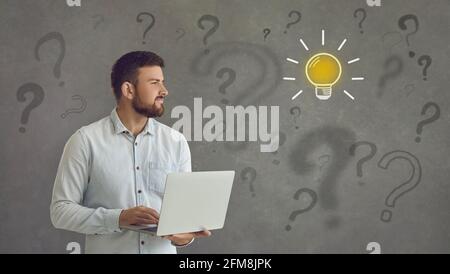 Businessman thinking of an idea on grey background with light bulb and question marks Stock Photo