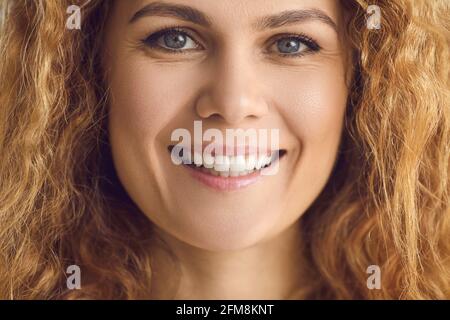 Extreme closeup portrait of a happy woman with wavy hair and a friendly white smile Stock Photo