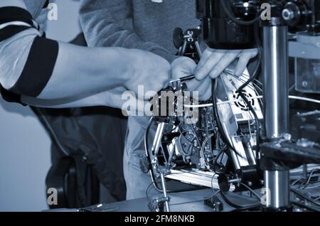 Two male masters work in the workshop with electronics, wires, 3d printer. Stock Photo