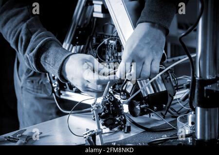 Two male masters work in the workshop with electronics, wires, 3d printer. Stock Photo