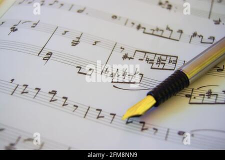 Fine gold-nibbed fountain pet set on a sheet of paper with musical notes written on it Stock Photo