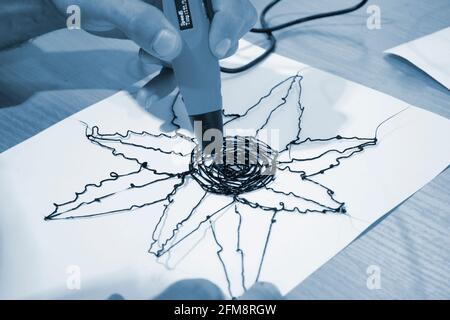 Man 3d pen draws a flower on white paper Stock Photo