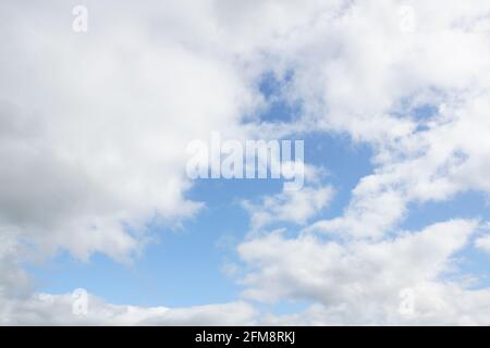 Hazy blue summer sky with whispy white cumulus clouds Stock Photo