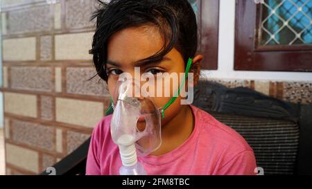 30 April 2021- Reengus, Sikar, India. Little cute girl infected with Covid virus. Girl admitted in hospital and receiving inhalation from Oxygen mask. Stock Photo