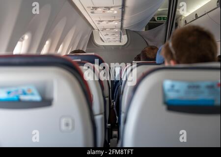 Interior of commercial airplane with unrecognizable passengers on their seats during flight shot from the rear of airplane. Passenger in a airplane ca Stock Photo