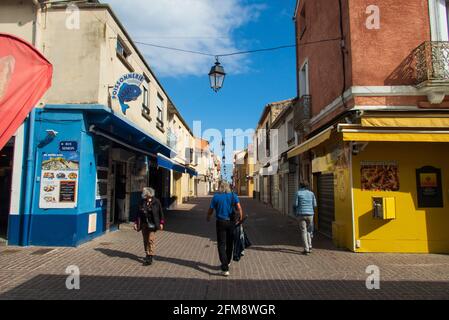 Three people walking in a paved street in Palavas les Flots, near Carnon Plage and Montpellier, Occitaine, south of France Stock Photo