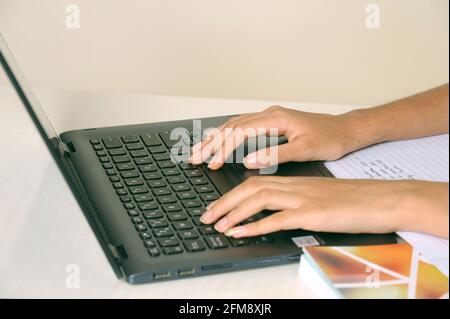Selective focus closeup portrait of beautiful teen hands typing on laptop keyboard indian girl working on computer Stock Photo