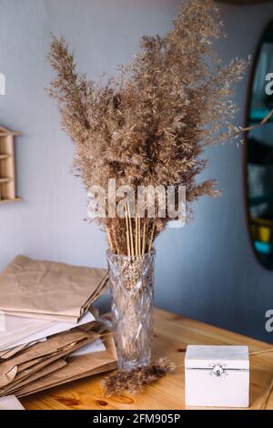 Dry reeds, reeds in vase, craft paper, wood and neutral colors in still life Stock Photo
