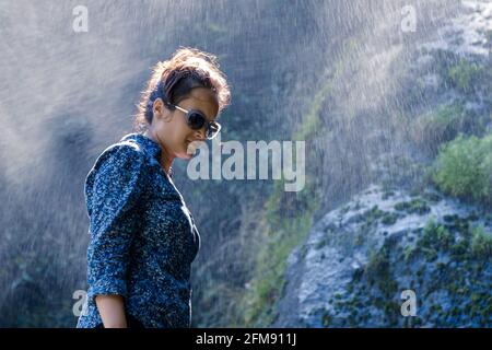 Young Nepalese woman standing in the water spray from a waterfall Stock Photo