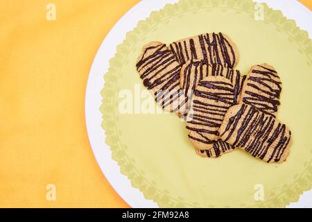 Butter cookies with chocolate on top on yellow background ready to eat. Copy space for text. Concept of homemade food. Stock Photo