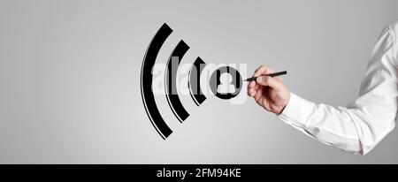 Businessman draws a wifi icon on gray background. Stock Photo