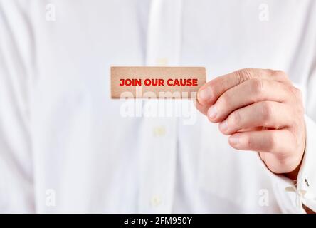 Male hand holds a wooden block with the message join our cause. Charity and relief work concept. Stock Photo