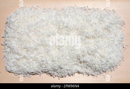 pile stack of raw organic coconut shavings sweet treat food background on wood cutting board Stock Photo