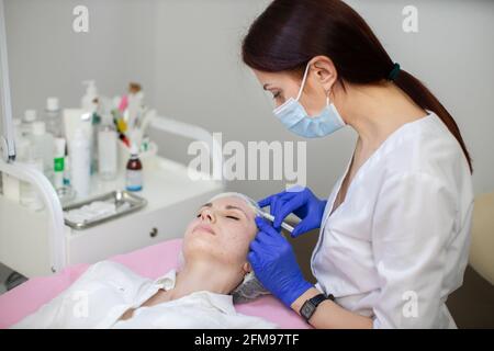 Aesthetic cosmetology in a beauty salon. Female cosmetologist makes rejuvenating botox anti wrinkle injections on the face of a beautiful woman. Skin revitalization, hydration Stock Photo