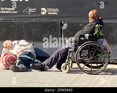 Homeless men strewn on a sidewalk sleeping in the morning sun near 7th Avenue by a new entrance to Penn Station in Manhattan, New York City. Stock Photo