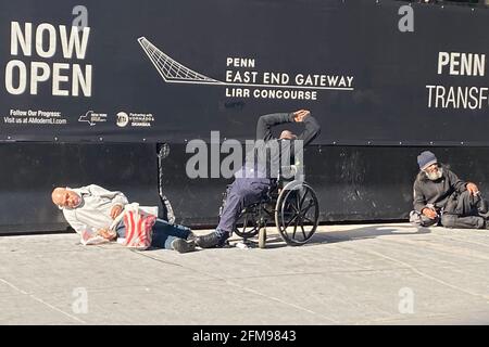 Homeless men strewn on a sidewalk sleeping in the morning sun near 7th Avenue by a new entrance to Penn Station in Manhattan, New York City. Stock Photo