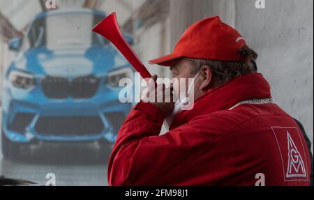 Leipzig, Germany. 07th May, 2021. A participant in a strike action by IG Metall stands in front of the BMW plant in Leipzig. In the collective bargaining dispute in the metal industry, IG Metall has called on the employees of the BMW plant to go on a 24-hour warning strike. The union is demanding, among other things, four percent pay increases and an improvement in the transfer regulations for trainees. Credit: Hendrik Schmidt/dpa-Zentralbild/dpa/Alamy Live News Stock Photo