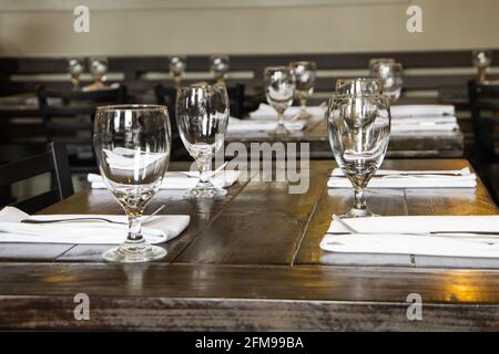 A water glass and a silverware setting for four on a wood table at a high end restaurant Stock Photo