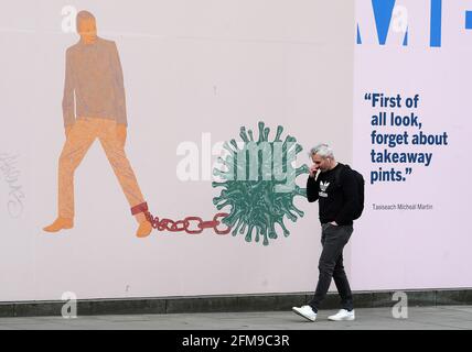 A man walks past part of the 'IN THESE STRANGE TIMES: an evolving series created in response to the pandemic' exhibition at the Science Gallery in Dublin's city centre. There have been four further deaths linked to Covid-19 and an additional 434 confirmed cases, the Department of Health has said. Dr. Holohan has called for caution as the country continues to open up. Picture date: Friday May 7, 2021. See PA story IRISH Coronavirus. Stock Photo