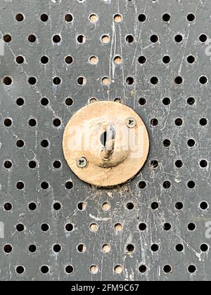 Painted metal hook fixed to perforated security screen on building Stock Photo