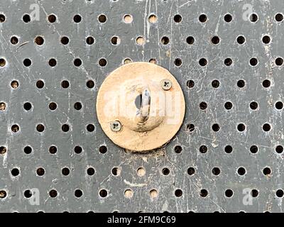 Painted metal hook fixed to perforated security screen on building Stock Photo