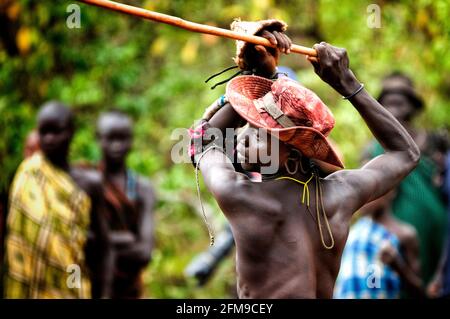 This Suri man raises his stick in battle. OMO VALLEY, ETHIOPIA: MEET THE tribe who engage in a violent and bloody stick fight with the last man standi Stock Photo
