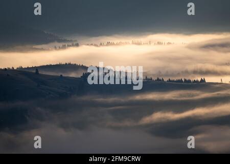 Misty morning landscape over Bucovina village. Sunrise over the foggy hills of the Romanian countryside Stock Photo