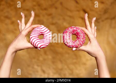shallow depth of field doughnuts in hands on yellow rock background. summertime food concept Stock Photo