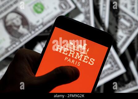 In this photo illustration the French high fashion luxury clothing manufacturer Hermes logo seen displayed on a smartphone with USD (United States dollar) currency in the background. (Photo by Budrul Chukrut / SOPA Images/Sipa USA) Stock Photo