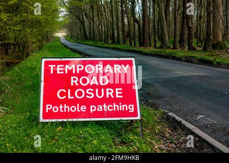 Sign saying temporary road closure pothole patching on a rural road in the Uk Stock Photo