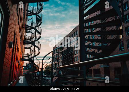 Spiral staircases in the old Warehouse District. Narrow canal and red brick buildings of Speicherstadt in Hamburg. After sunset. Stock Photo