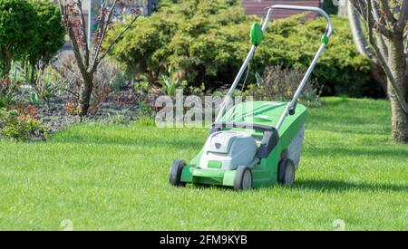 Lawn mower on a green lawn. Trimming the grass on the lawn in the garden. Stock Photo