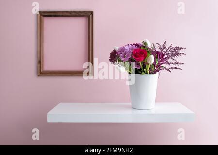 Flower vase on a floating shelf minimalist interior design with blank picture frame Stock Photo