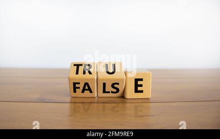 False or true symbol. Turned wooden cubes and changed the word 'false' to 'true' or vice versa. Beautiful wooden table, white background, copy space. Stock Photo