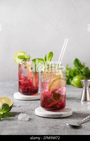 Two blueberries mojito with lime, mint and ice cube on gray background. Vertical format. Stock Photo