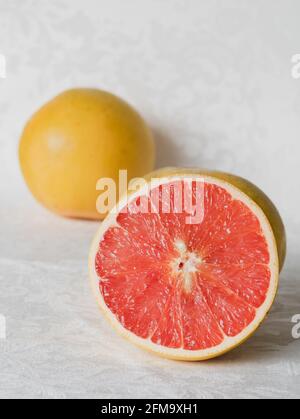Half a Pink Grapefruit with Whole Grapefruit in Background Stock Photo