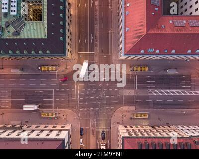 Aerial shot of an urban crossing road in a city with bend of cars from a top down view at the street between houses Stock Photo