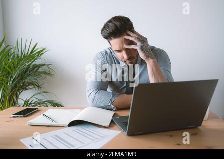 A handsome man in a shirt and tie working on a computer in his office Stock Photo
