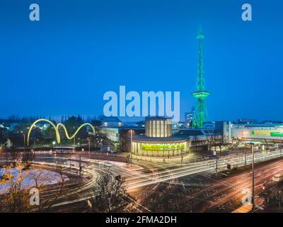 Road traffic at the Berlin exhibition center with illuminated radio tower in the evening. Stock Photo