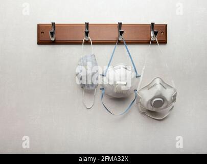 Close up several white disposable facepiece respirator masks with exhalation valves hanging on clothes rack as essential safety accessory during pande Stock Photo