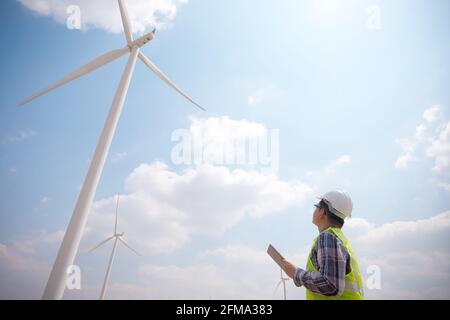 Successful engineer windmills using tablet with wind turbine in background Stock Photo