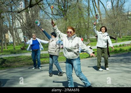 Dnepropetrovsk, Ukraine - 04.22.2021: A group of seniors doing health and fitness gymnastics in the park. Old men do tennis ball and racket exercises. Stock Photo