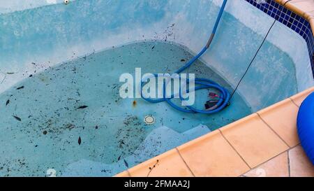 Electric pump in bottom of dirty leaking swimming pool removing water so the pool can be repaired Stock Photo