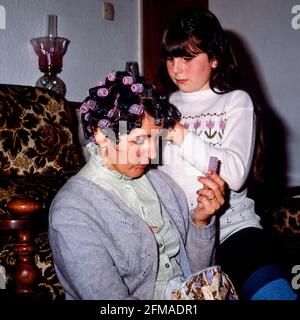 young girl putting rollers in her mothers hair at home 1980s england uk Stock Photo