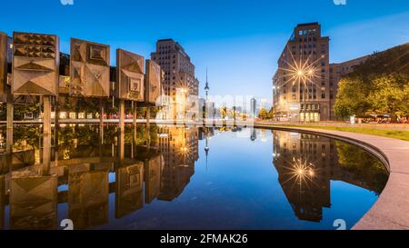 Reflection of the buildings on Strausberger Platz in the water of the fountain with the television tower in the background at the blue hour. Stock Photo