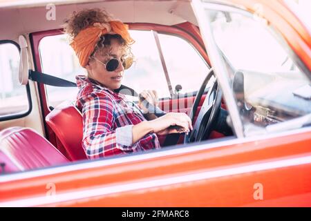 Woman holding using safety belt inside the car viewed from outside - concept of insurance and female people driver - trendy youthful lady enjoy travel and drive vehicle for transport activity Stock Photo