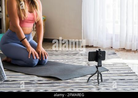 Shot of fitness woman sitting on yoga mat and using mobile phone. Fit young woman using cellphone while doing exercise at home. content creator modern business people online internet Stock Photo