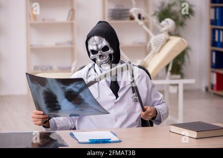 Devil doctor radiologist examining skeleton patient at the hospital Stock Photo